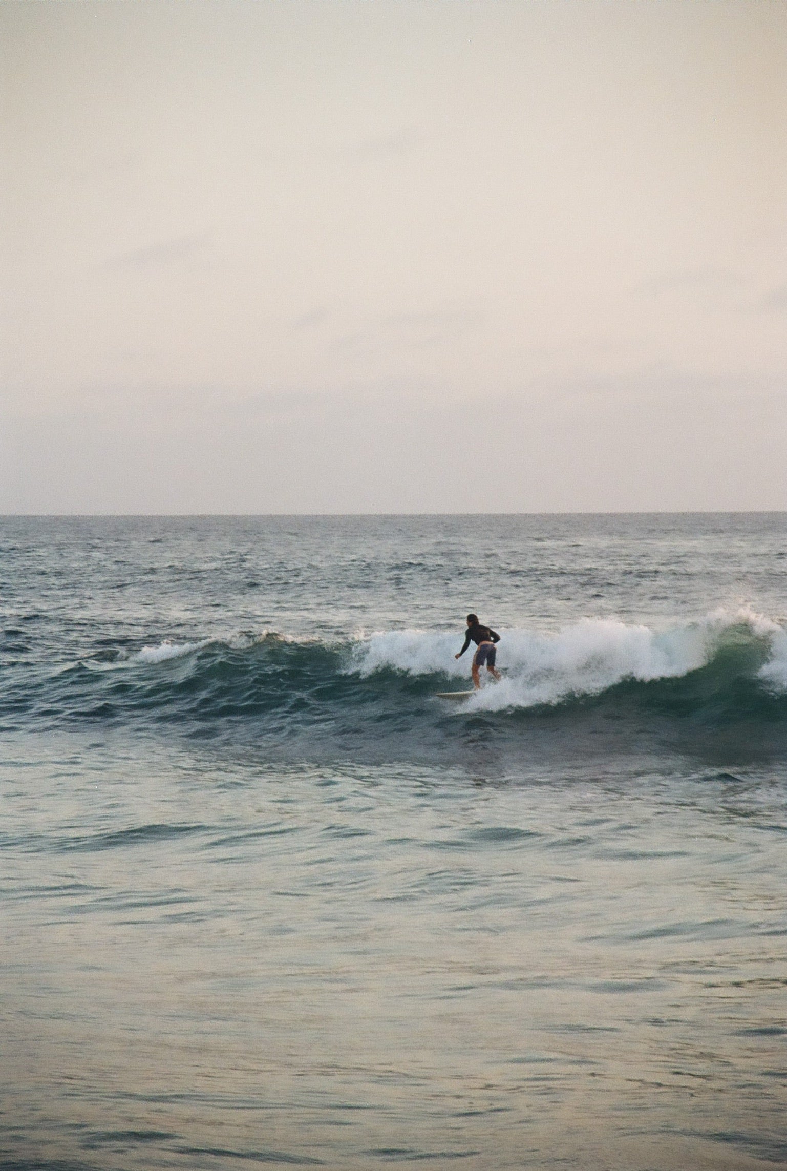 Surfer riding a wave at dusk — reef-safe mineral zinc oxide sunscreen for surfers and water sports
